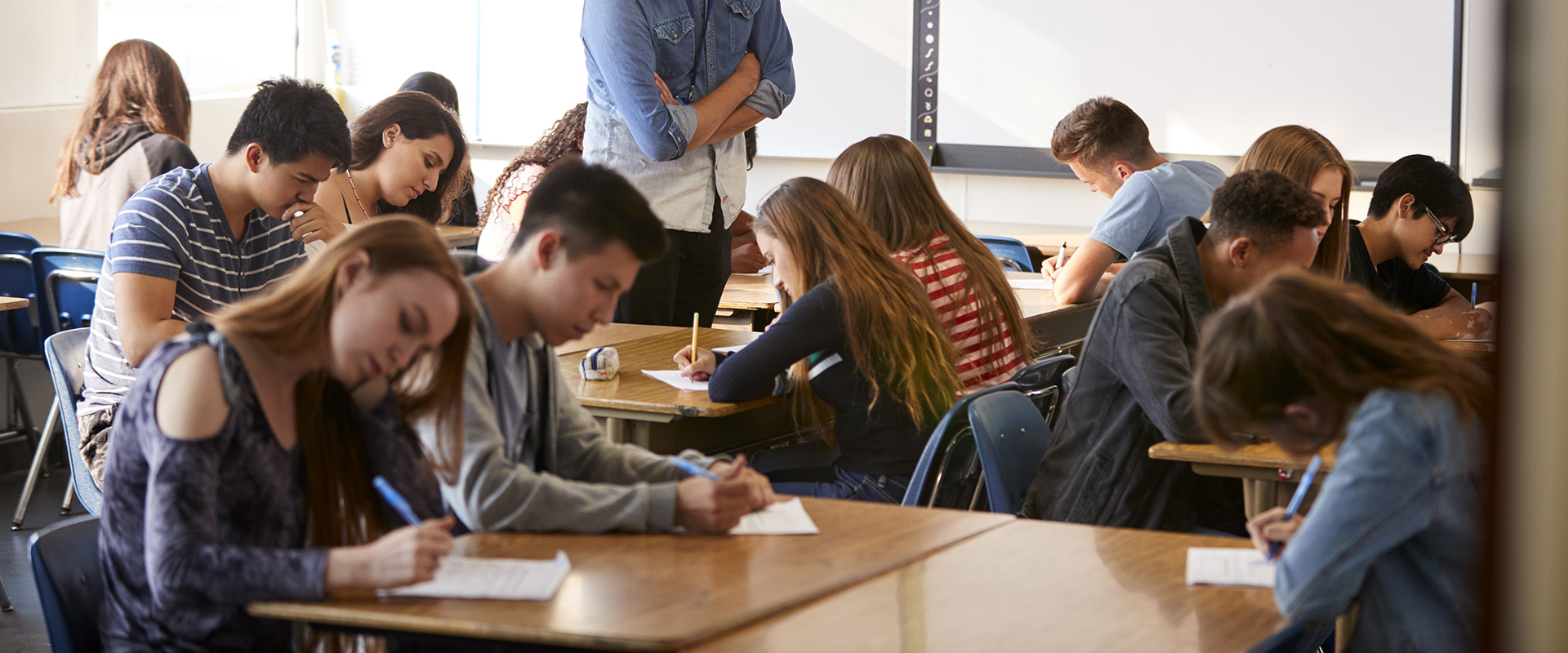 Male High School Teacher Standing By Interactive Whiteboard Teaching Lesson