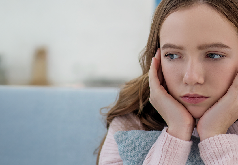 Mujer joven con expresión preocupada apoyando la cabeza en la mano
