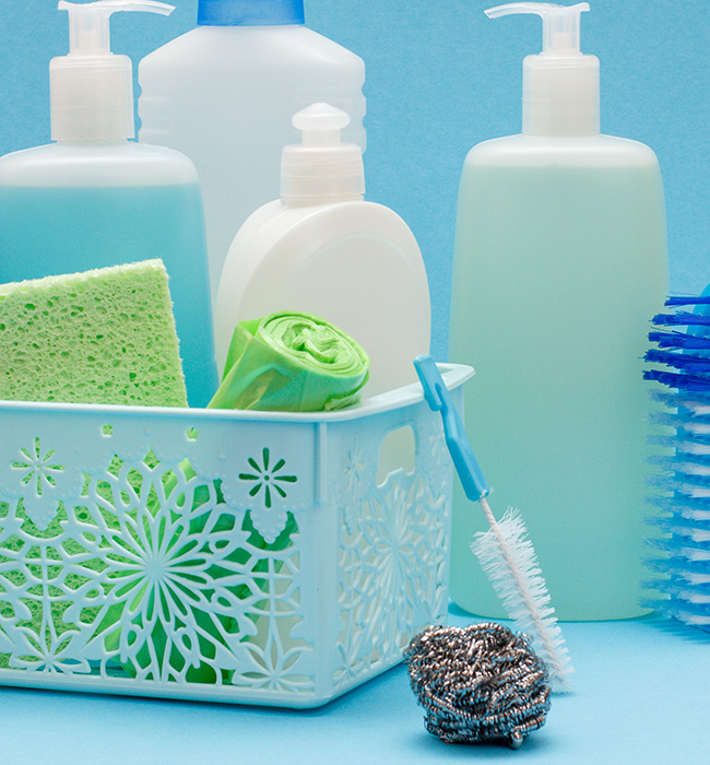 Productos de limpieza organizados en una cesta sobre un fondo azul.