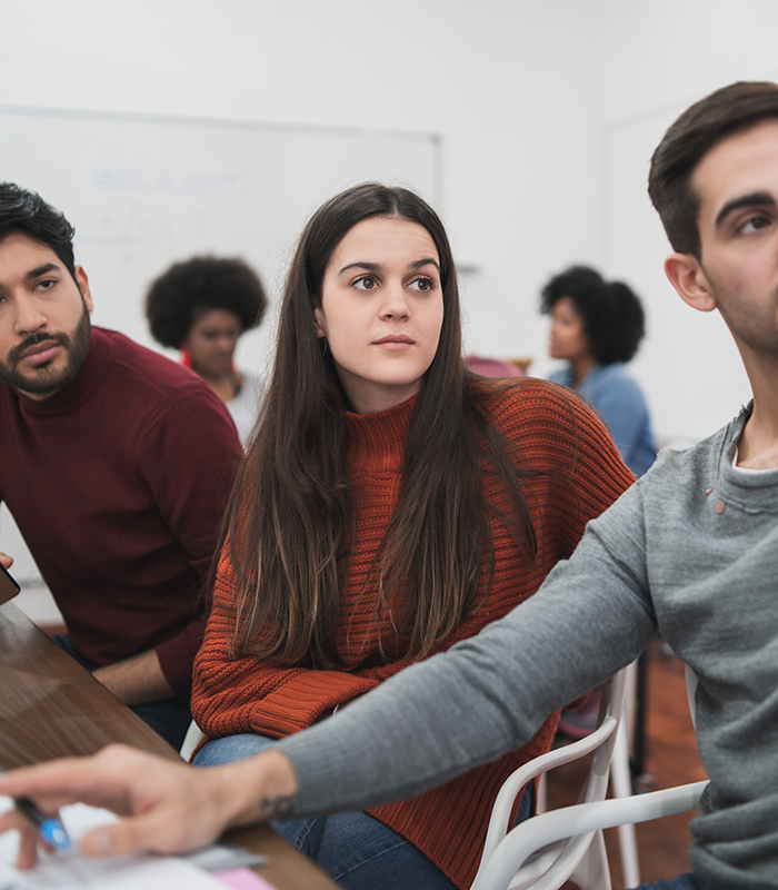 Jóvenes en una reunión o clase mirando hacia el frente.
