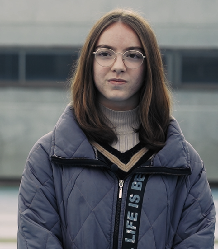 Retrato de chica con gafas y abrigo oscuro en exterior. Reyes Martínez, alumna de Colegio de Navidad Piquer.