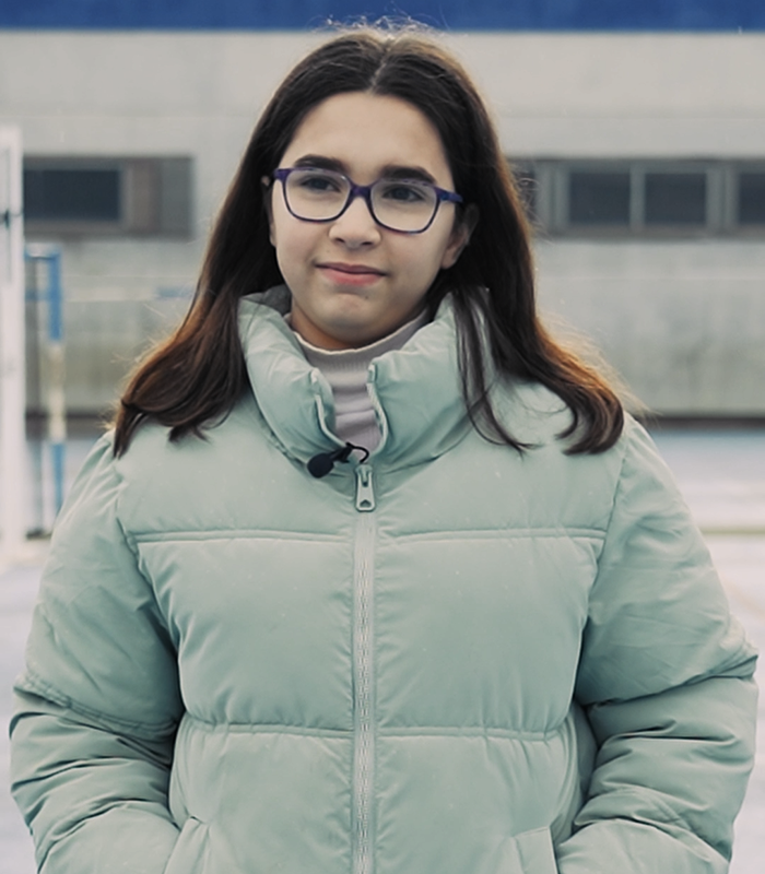 Retrato de chica con gafas y abrigo verde claro en exterior. Sara Martínez, alumna de Colegio de Navidad Piquer