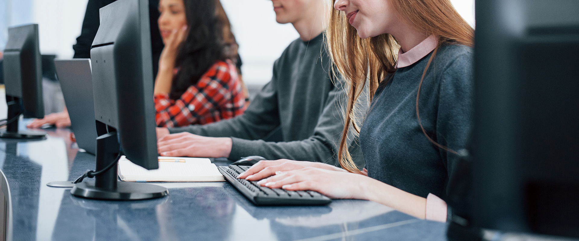 Alumnos escribiendo en ordenadores durante una clase